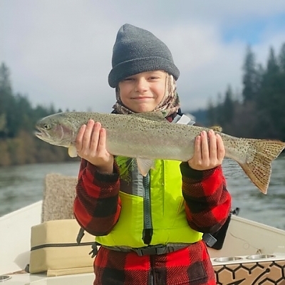 Child holding up fish on boat.