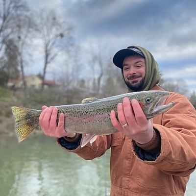 Young man on fishing trip holds up fish