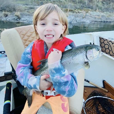 Child holding up fish on boat.