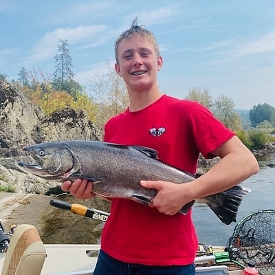 Teen boy holds up fish caught on cloudy day